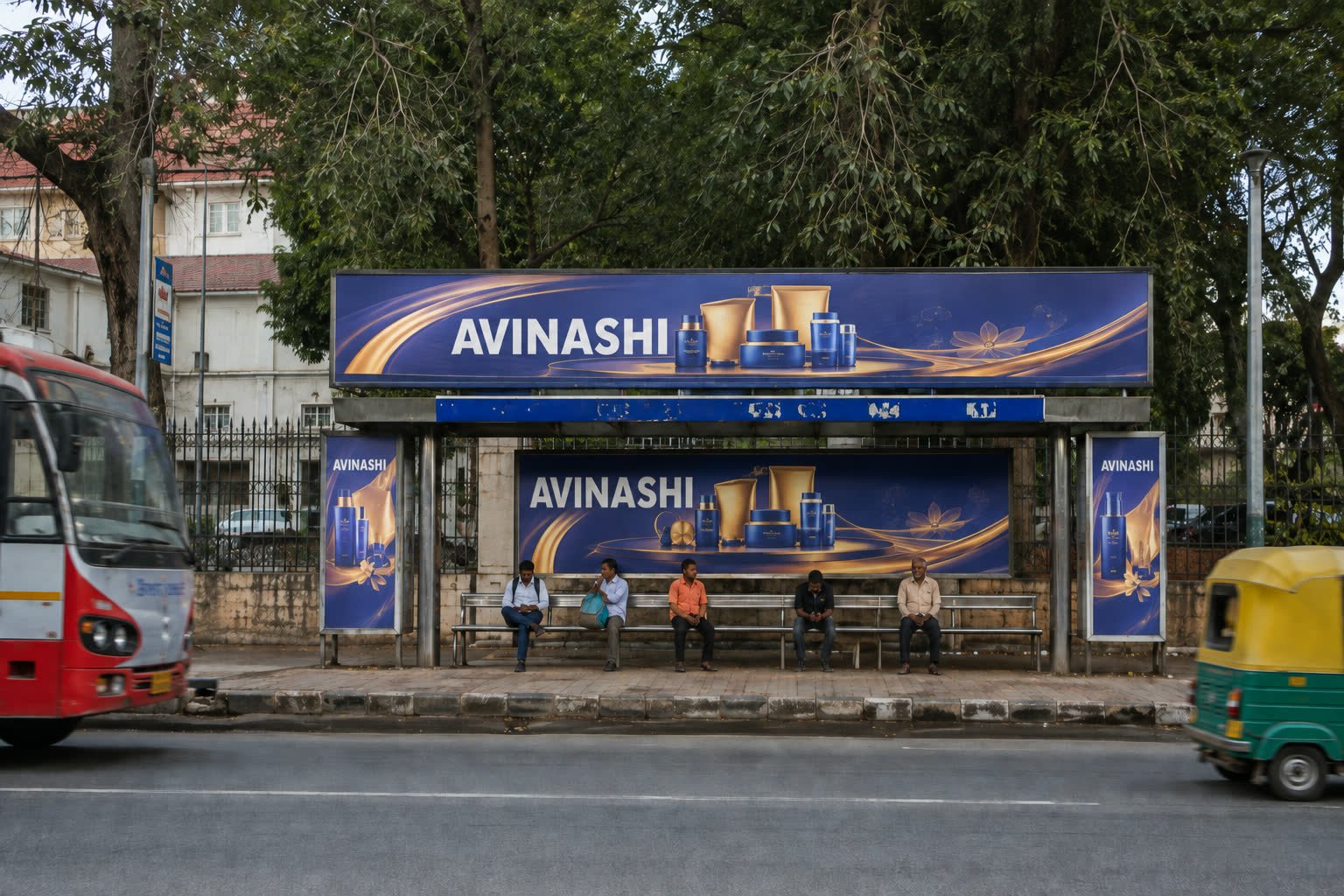 Bus shelter advertising on a tree-lined Mysuru avenue during the day